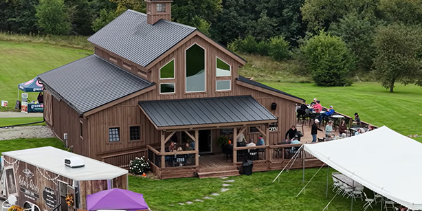A large barn with people gathered on a patio 